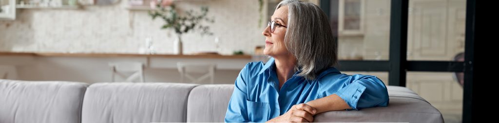 Calm relaxed mature older woman relaxing sitting on couch at home