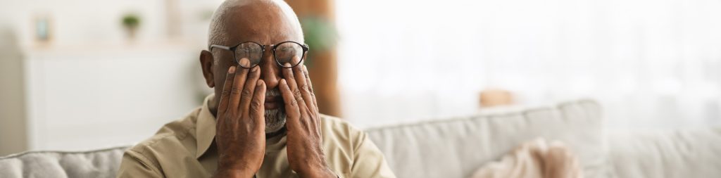 tired older man holding hands to face