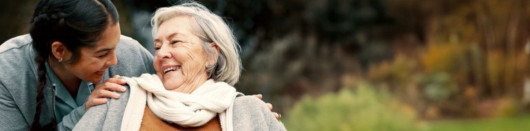 Older women laughing with caregiver outside